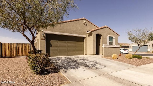 mediterranean / spanish house featuring a tile roof, stucco siding, fence, a garage, and driveway