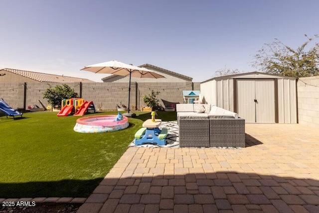 view of patio featuring a playground, an outdoor structure, a fenced backyard, and a storage shed