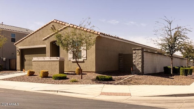 view of front of house with an attached garage, a tile roof, concrete driveway, and stucco siding