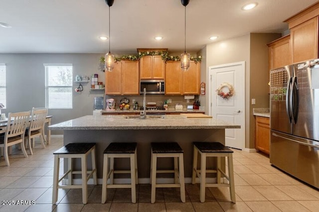 kitchen featuring light tile patterned floors, appliances with stainless steel finishes, a breakfast bar area, and light stone countertops