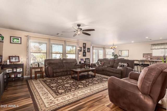 living room featuring dark hardwood / wood-style floors, ceiling fan with notable chandelier, and ornamental molding