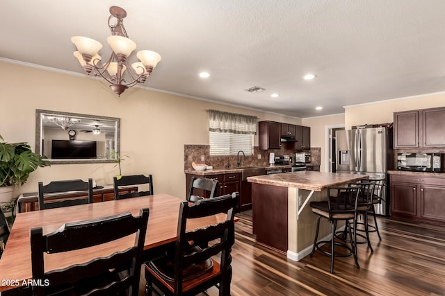 dining area featuring sink, dark hardwood / wood-style flooring, crown molding, and a notable chandelier