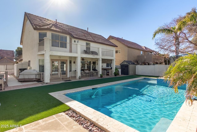 back of house featuring a balcony, a fenced in pool, a yard, and a patio