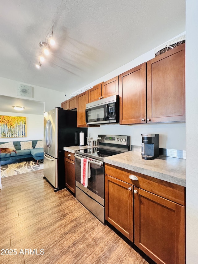 8343 E Edward Ave, Scottsdale, AZ 85250 - kitchen featuring stainless steel appliances, light wood finished floors, light countertops, brown cabinets, and a textured ceiling