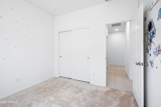 unfurnished bedroom with a closet and light colored carpet