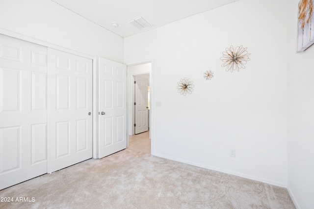 unfurnished bedroom with a closet and light carpet