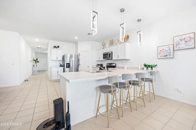 kitchen with decorative light fixtures, light tile patterned floors, kitchen peninsula, appliances with stainless steel finishes, and white cabinets