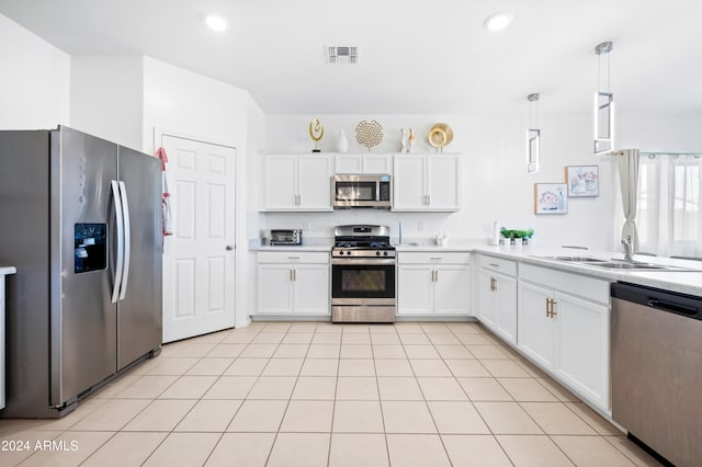 kitchen featuring white cabinets, decorative light fixtures, sink, appliances with stainless steel finishes, and light tile patterned flooring