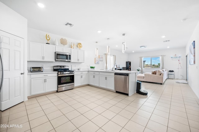 kitchen with hanging light fixtures, stainless steel appliances, kitchen peninsula, and white cabinetry