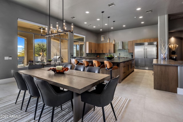 dining area featuring ceiling fan, sink, and a high ceiling