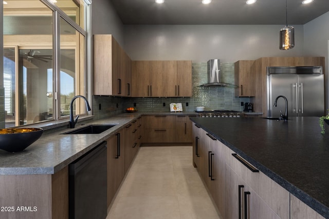 kitchen featuring pendant lighting, wall chimney range hood, stainless steel built in refrigerator, black dishwasher, and sink