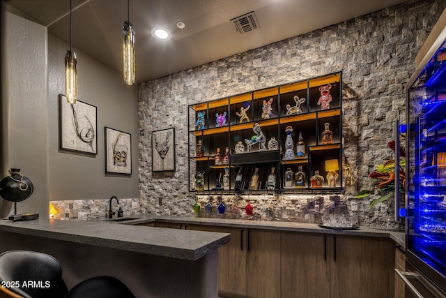 bar featuring sink and hanging light fixtures