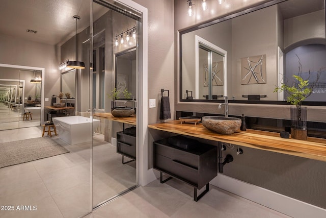 bathroom with tile patterned floors, vanity, and a bath