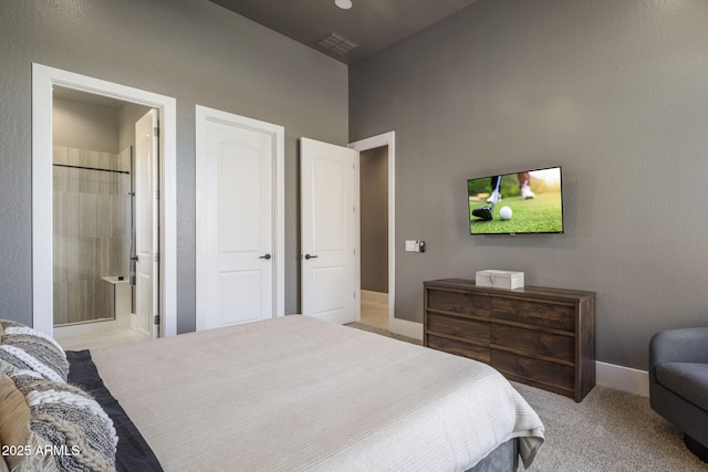 bedroom with ensuite bathroom and light carpet