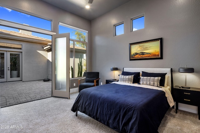 bedroom featuring light carpet, a towering ceiling, and french doors