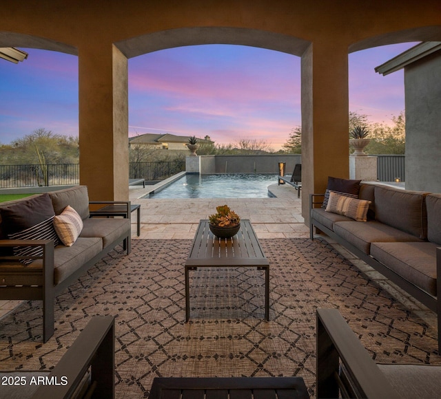 patio terrace at dusk featuring a fenced in pool, outdoor lounge area, and pool water feature