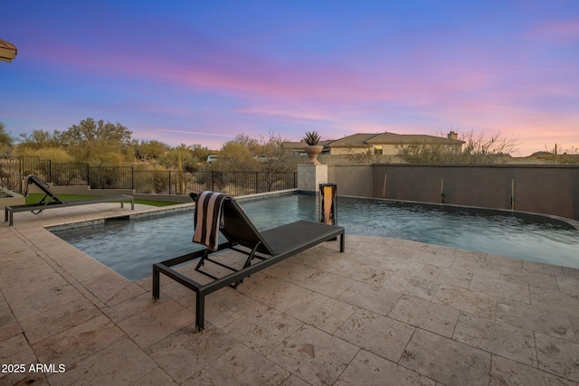 pool at dusk with a patio area and pool water feature