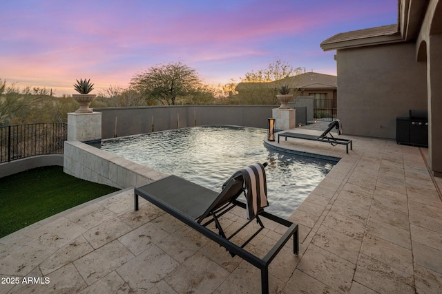 pool at dusk with a patio area and pool water feature