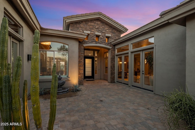 exterior entry at dusk featuring a patio area and french doors