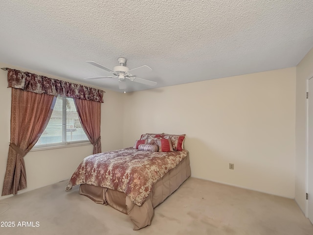 bedroom featuring a ceiling fan, a textured ceiling, and light colored carpet