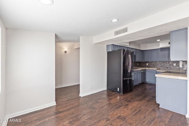 kitchen with tasteful backsplash, visible vents, dark wood-style flooring, freestanding refrigerator, and light countertops