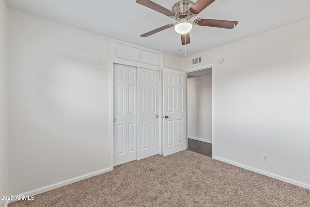 unfurnished bedroom featuring a closet, dark carpet, visible vents, and baseboards