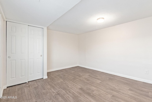 unfurnished bedroom featuring a closet, baseboards, and wood finished floors