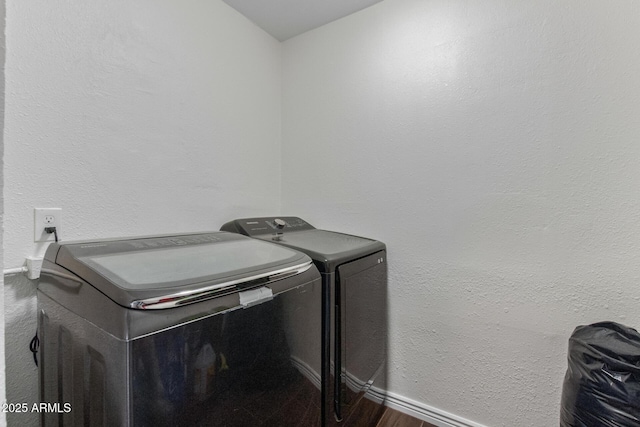 laundry room with a textured wall, laundry area, baseboards, washer and dryer, and dark wood-style floors