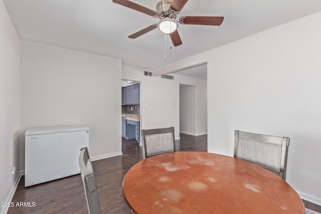 dining space featuring dark wood-type flooring, visible vents, baseboards, and a ceiling fan