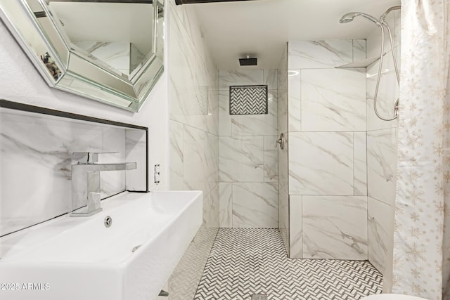 bathroom with tiled shower and sink