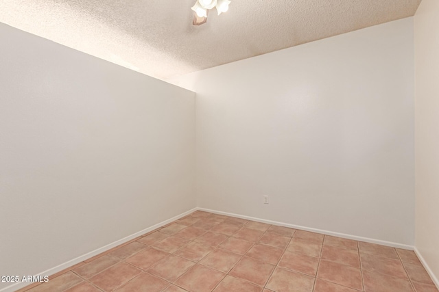 spare room featuring light tile patterned flooring and a textured ceiling