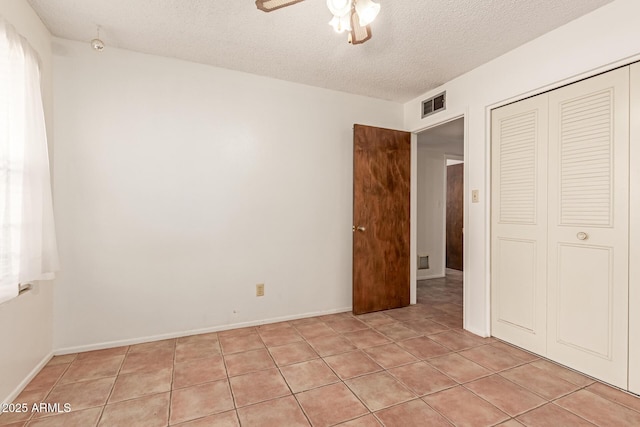 unfurnished bedroom with a textured ceiling, a closet, ceiling fan, and light tile patterned flooring