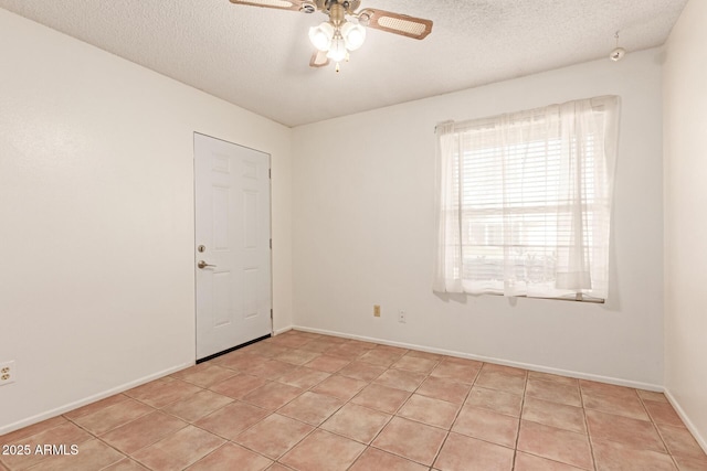 tiled empty room featuring ceiling fan and a textured ceiling