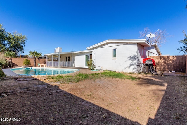 back of property with a fenced in pool