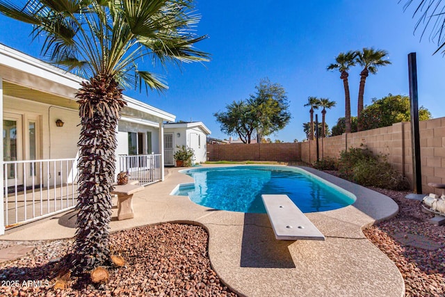 view of swimming pool with a diving board and a patio