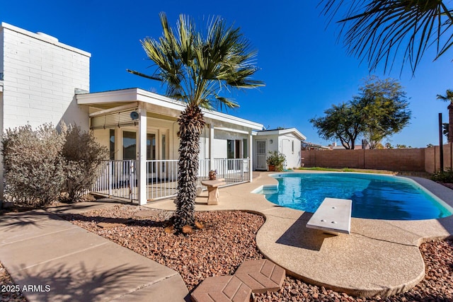 view of pool with a diving board, an outbuilding, and a patio area