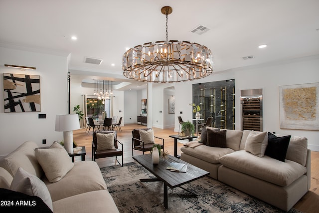 living room featuring crown molding, wood-type flooring, a chandelier, and beverage cooler