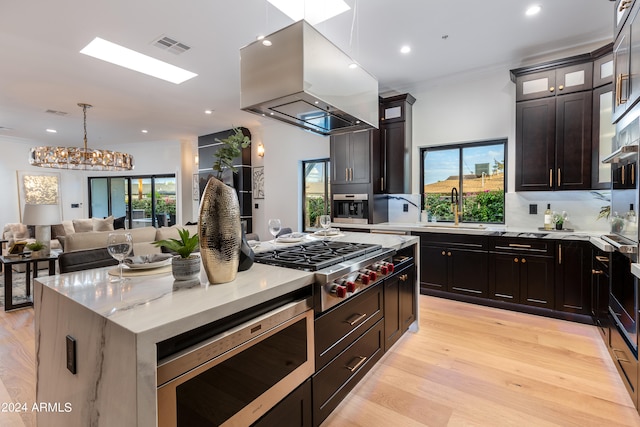 kitchen with appliances with stainless steel finishes, plenty of natural light, island range hood, and sink