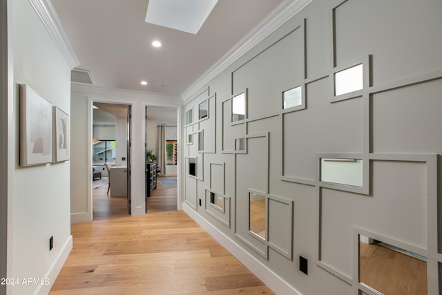 hallway featuring a skylight, light hardwood / wood-style floors, and crown molding