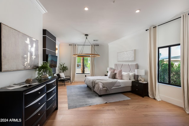 bedroom featuring light hardwood / wood-style flooring, ornamental molding, and multiple windows