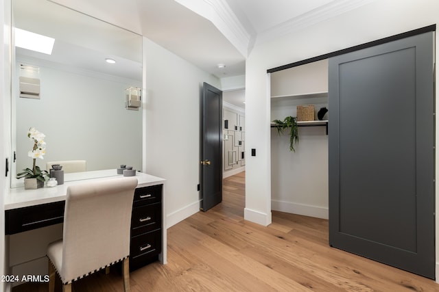 office area with light wood-type flooring, ornamental molding, a skylight, and built in desk