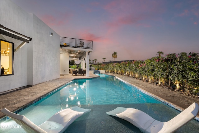 pool at dusk featuring a water slide and a patio area