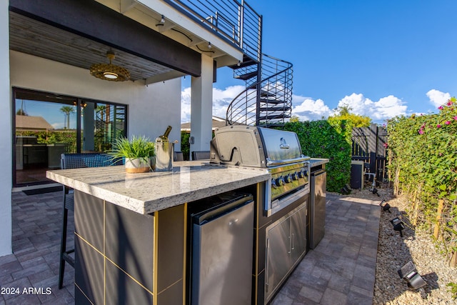 view of patio / terrace with a balcony, exterior kitchen, an outdoor bar, and area for grilling