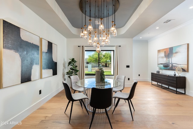 dining space featuring ornamental molding, an inviting chandelier, and light hardwood / wood-style flooring