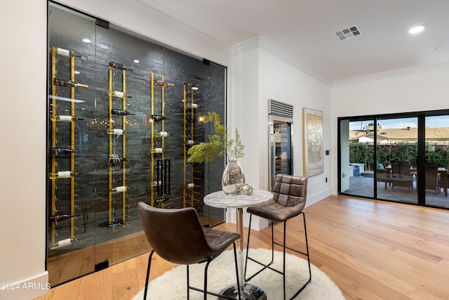 wine room with light hardwood / wood-style floors and ornamental molding