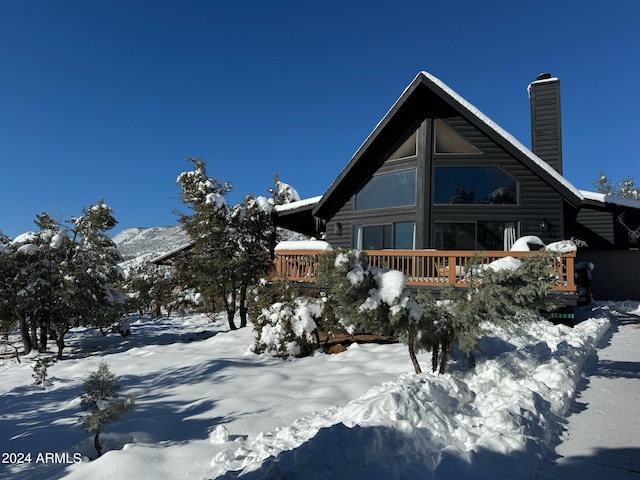 snow covered back of property featuring a wooden deck