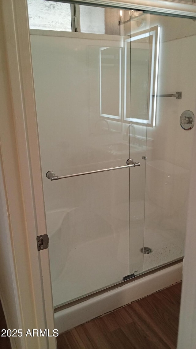 bathroom with wood-type flooring and a shower with door