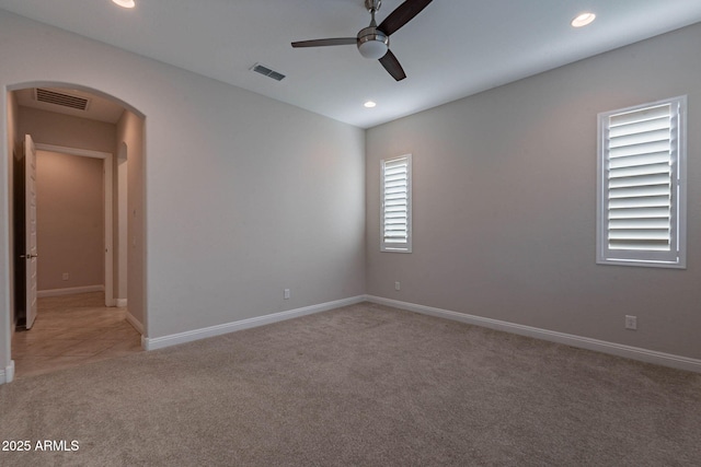 unfurnished room with light carpet, visible vents, arched walkways, and recessed lighting