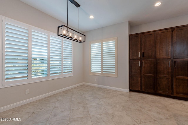 unfurnished bedroom with recessed lighting, baseboards, and an inviting chandelier