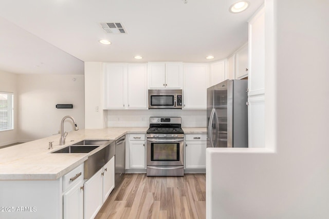 5450 E Deer Valley Dr Unit 1211, Phoenix, AZ 85054 - kitchen with stainless steel appliances, a peninsula, white cabinetry, light wood-style floors, and recessed lighting